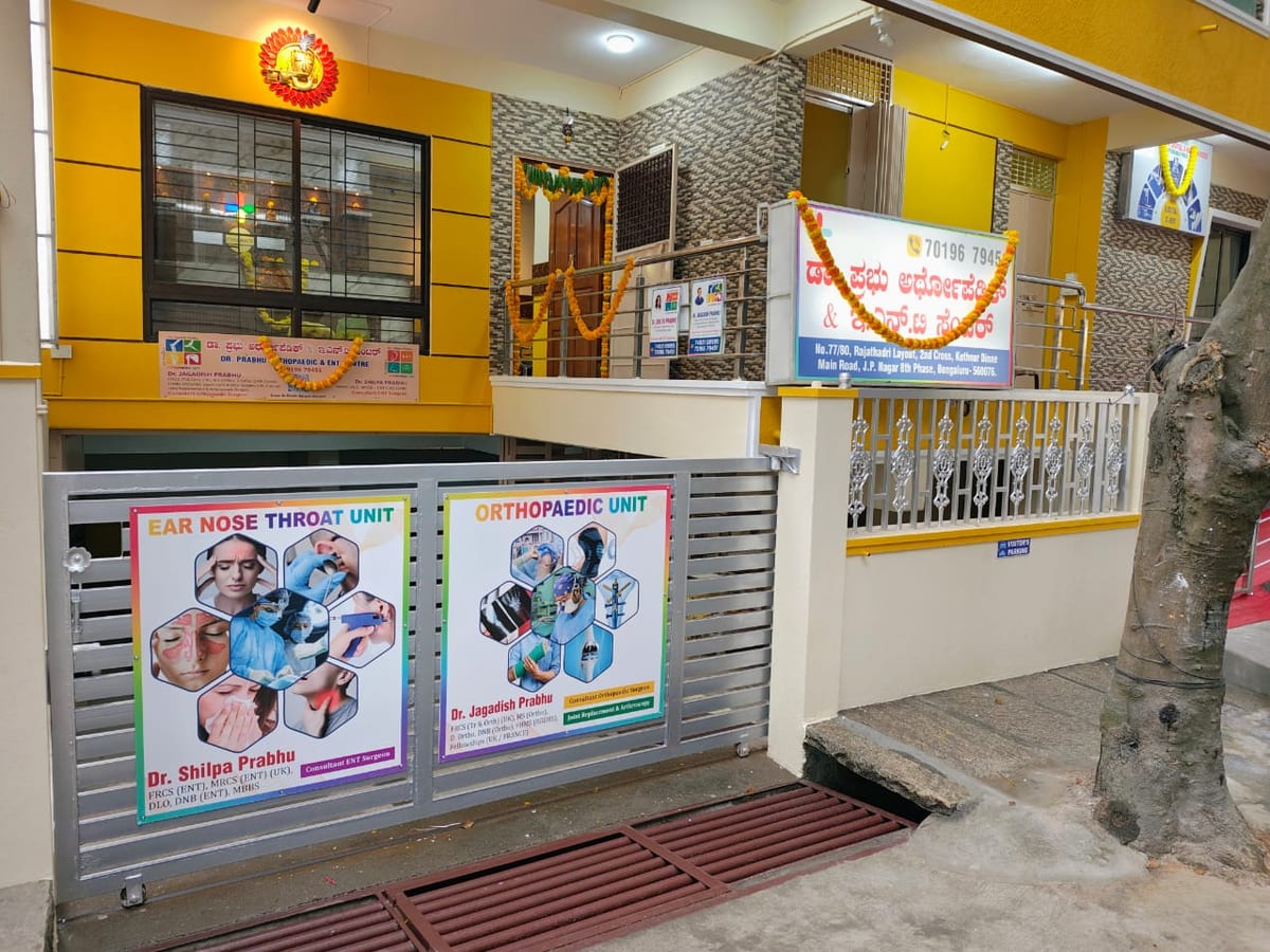 Yellow ENT clinic exterior in J.P. Nagar with entrance ramp, railings and service posters
