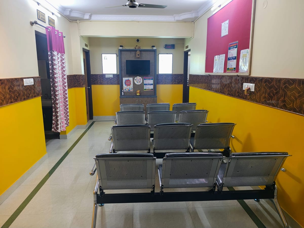 Waiting area with rows of metal chairs, yellow walls and a door at the far end