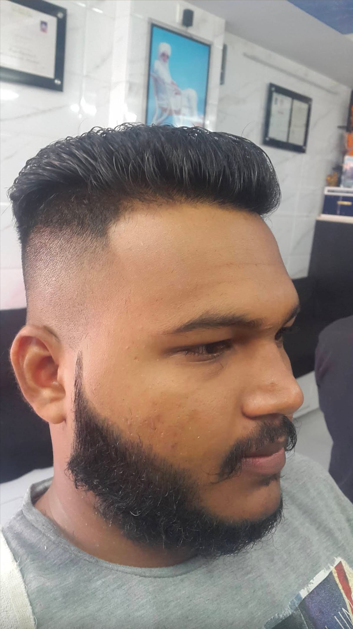 Side profile of a man with a faded haircut and trimmed beard in the barbershop