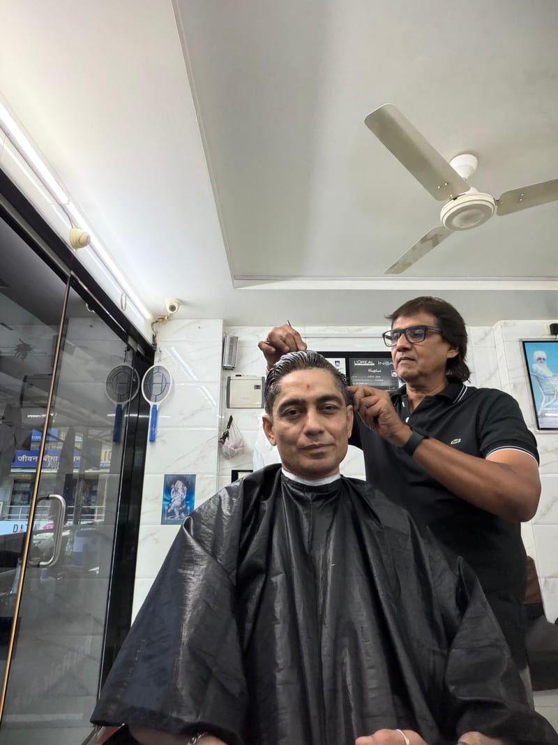 Barber cutting a seated customer's hair in a black cape