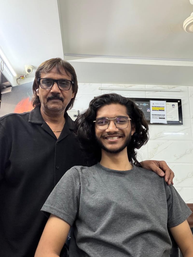 Two people posing together indoors beside a wall display