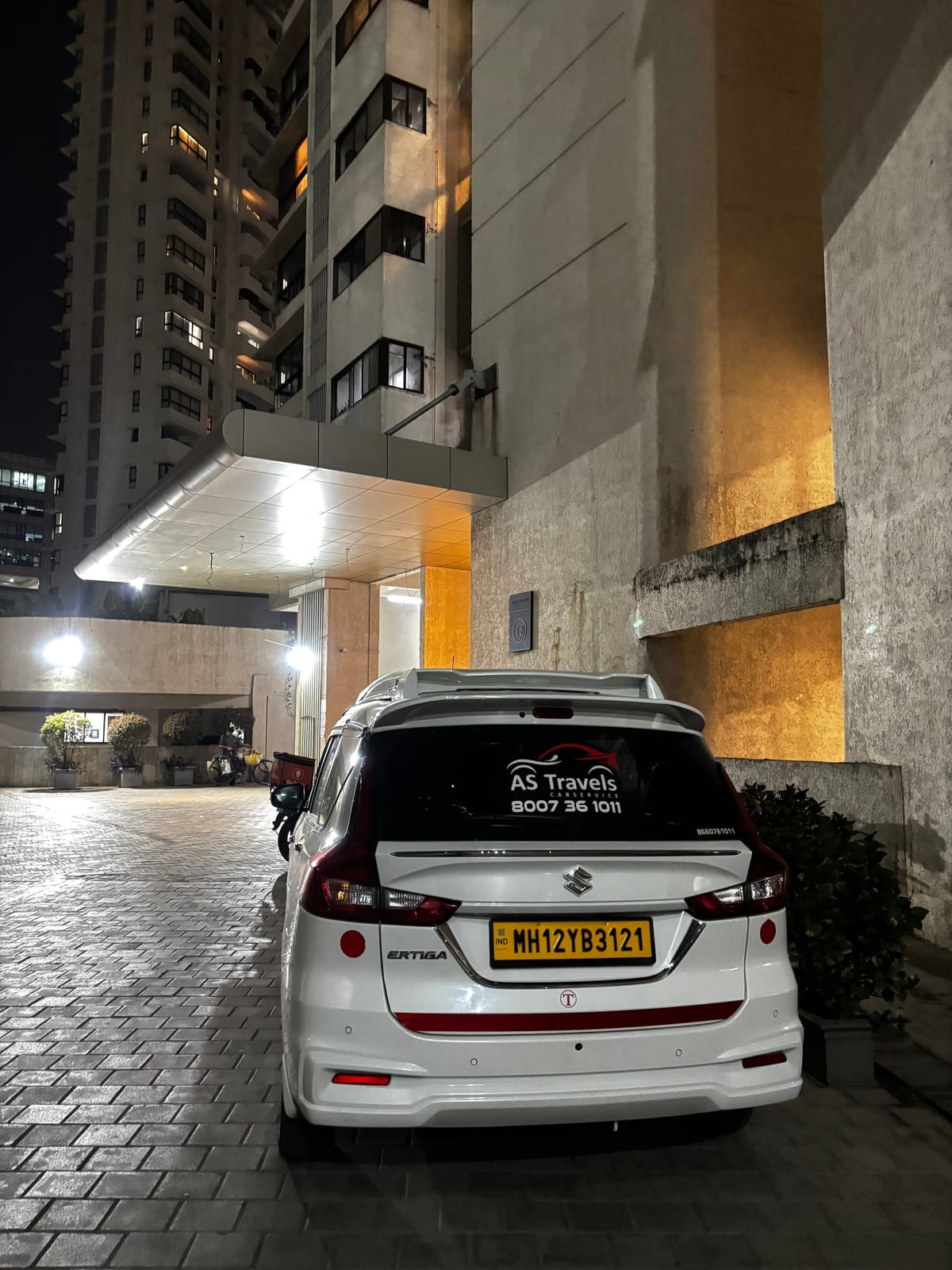 White Toyota Innova parked at a covered building entrance at night