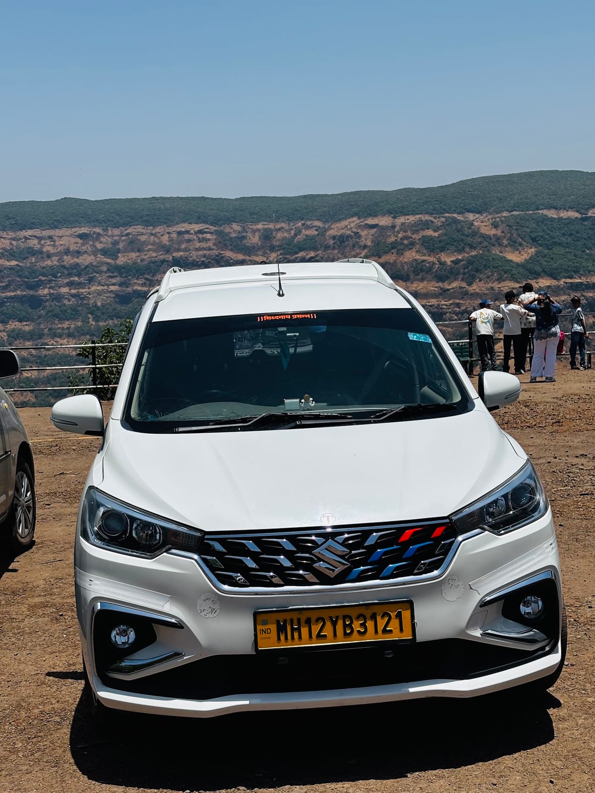 White passenger van parked at a mountain viewpoint with hills behind