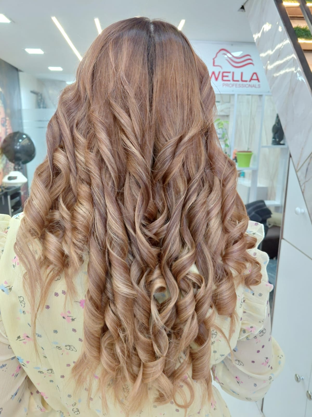 Long curled hairstyle with a Wella Professionals sign in the background
