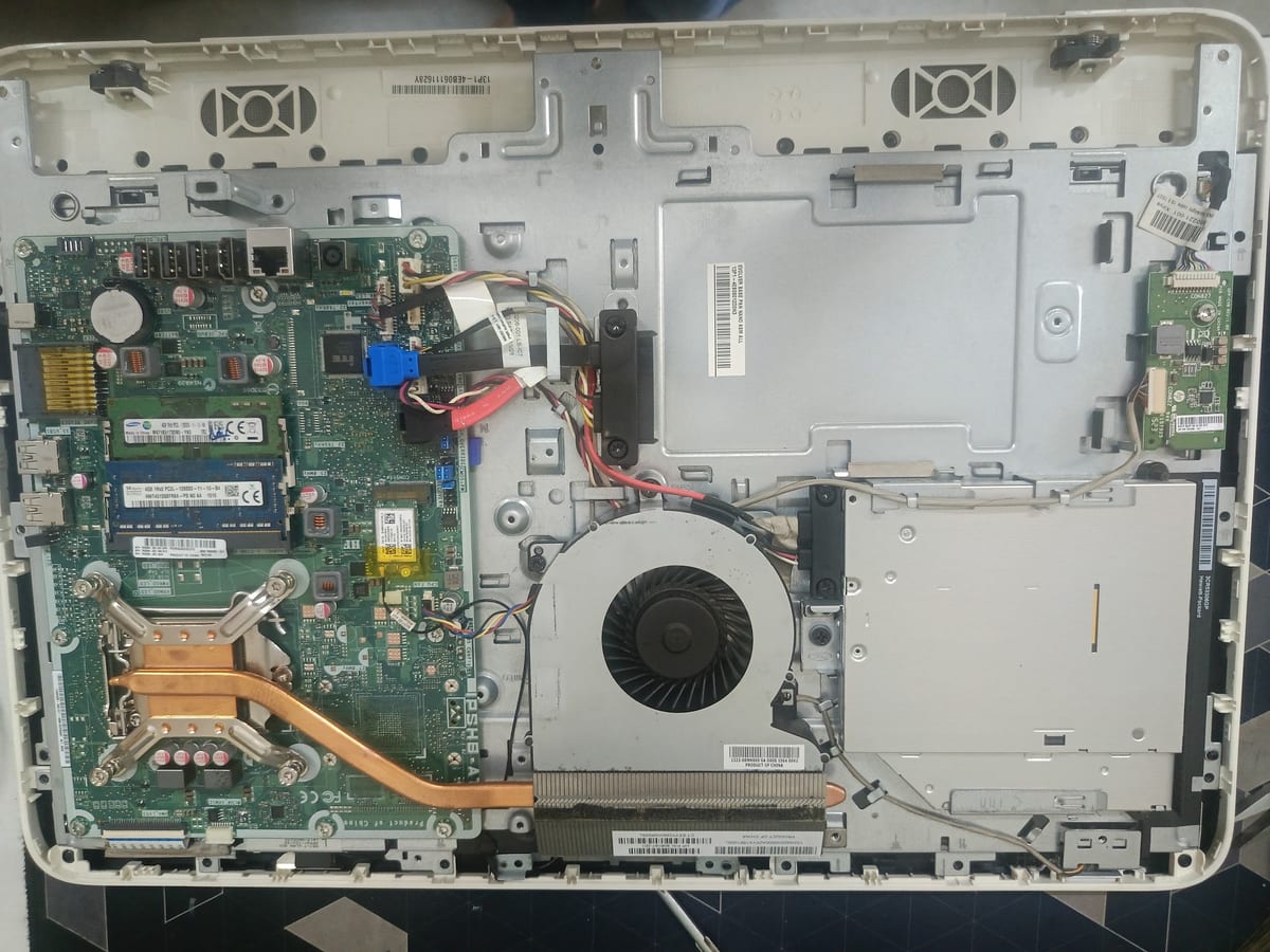 Opened laptop showing circuit board, cooling fan, heat pipe and internal parts