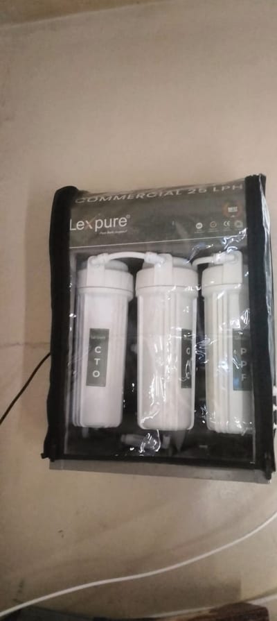 Packaged water filtration system with three white filter cartridges in clear wrapping