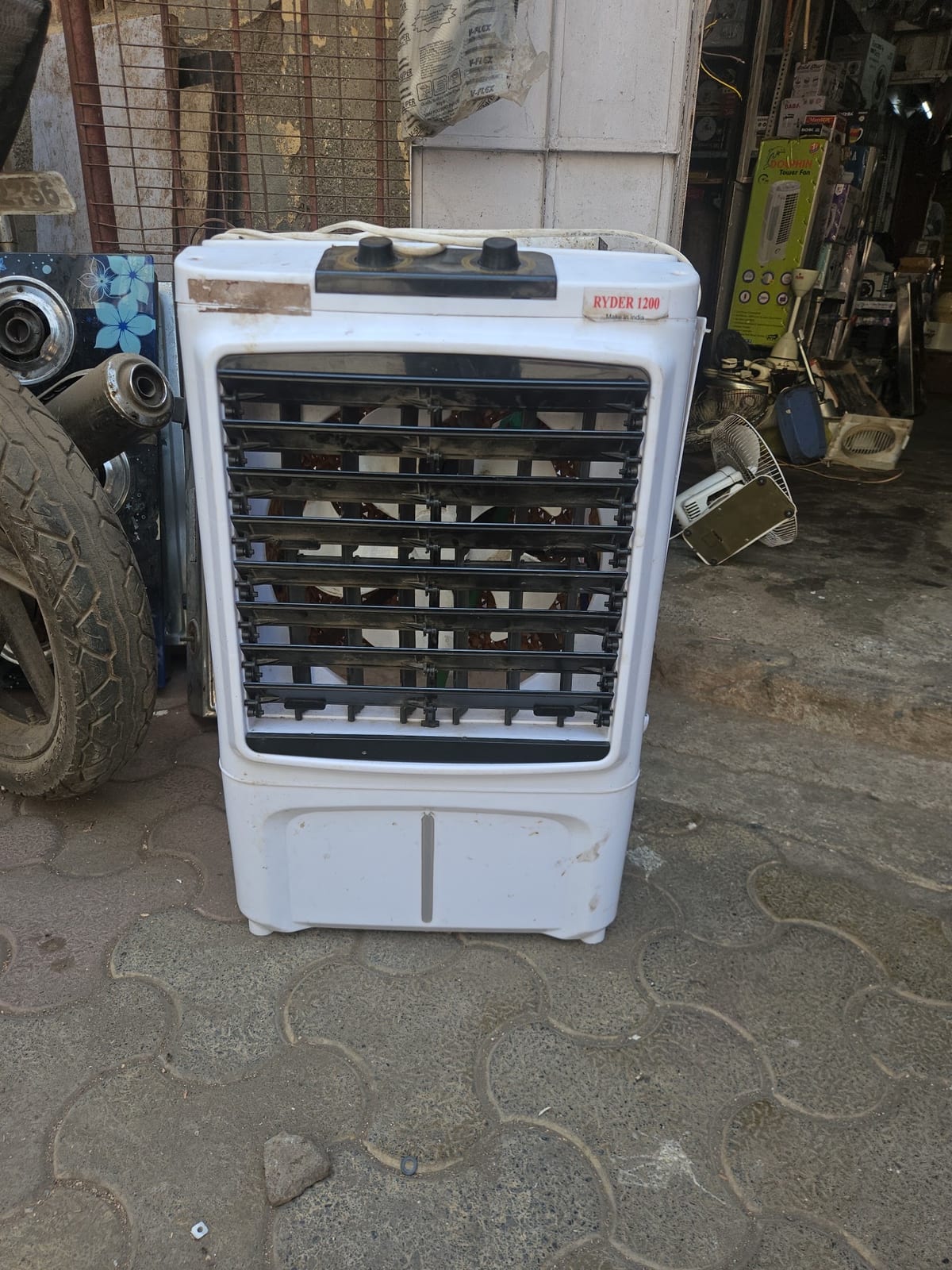 White evaporative air cooler on the sidewalk outside the shop
