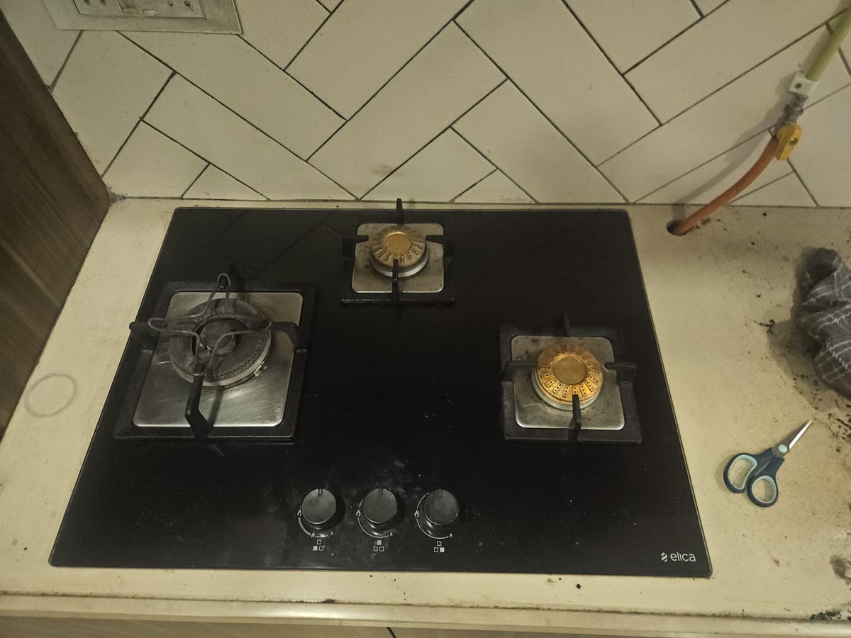 Three-burner black glass gas cooktop with control knobs