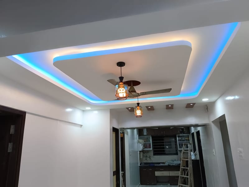 Room with recessed blue ceiling lighting, pendant lights and a ceiling fan