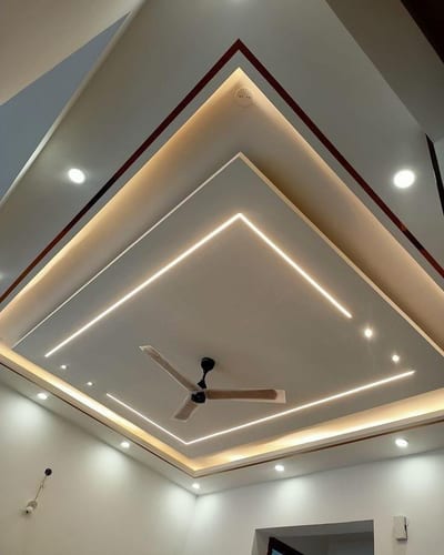 Layered geometric ceiling panels with recessed lighting and a ceiling fan