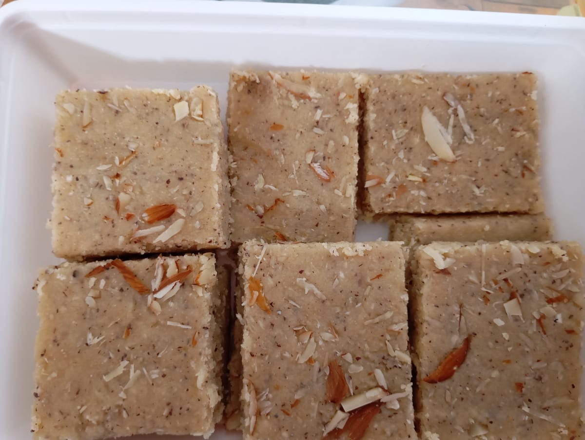 Rectangular almond and coconut topped dessert pieces in a white tray