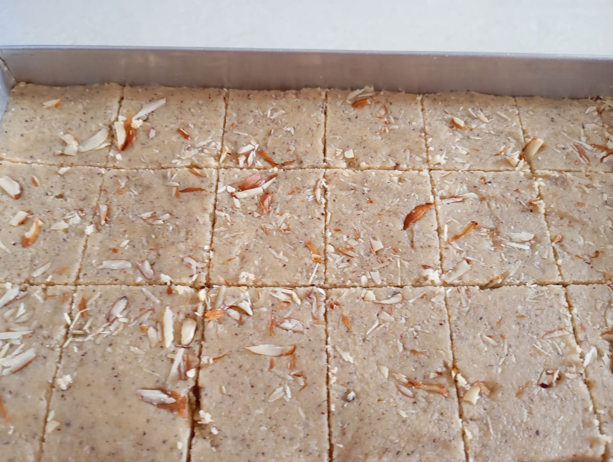 Beige confection topped with slivered nuts in a tray