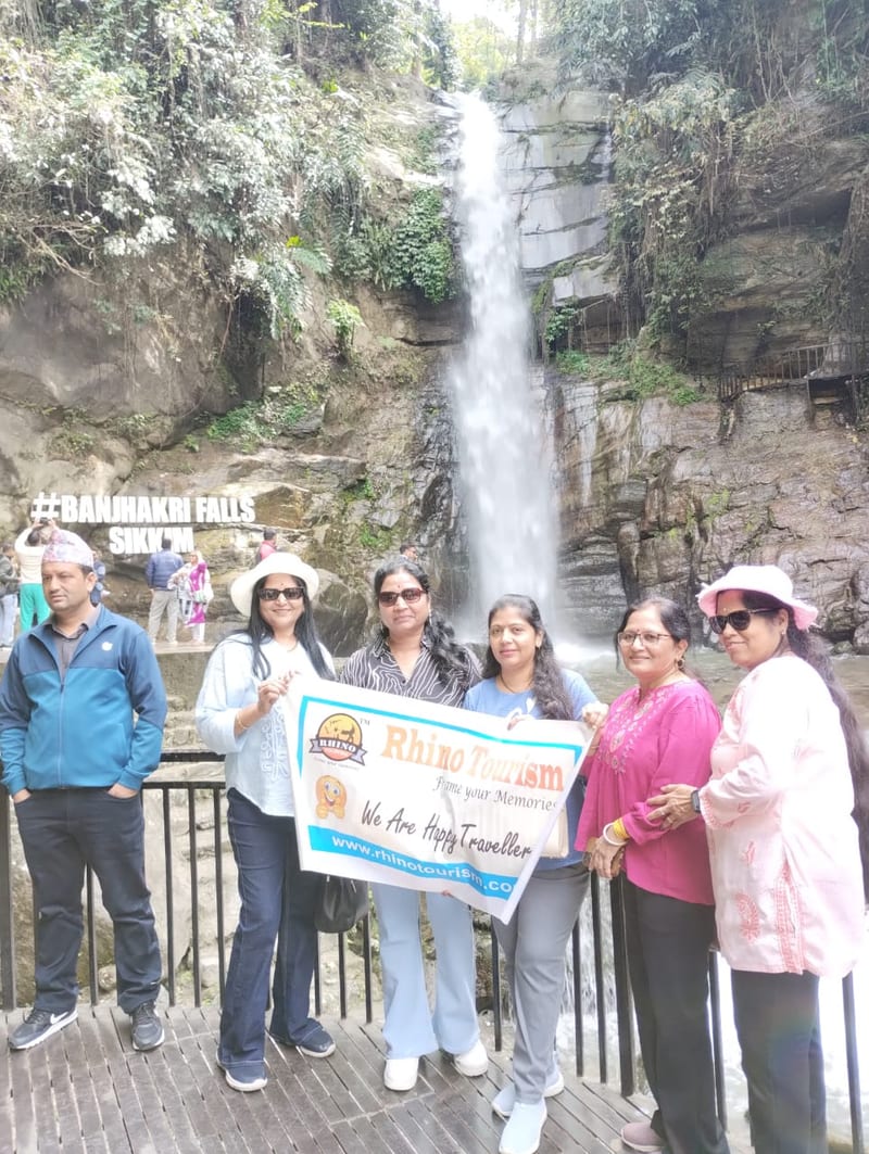 Six travelers holding a banner in front of a waterfall
