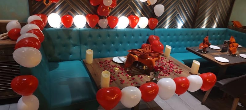 Seating area with teal booths, decorated tables and red and white balloons