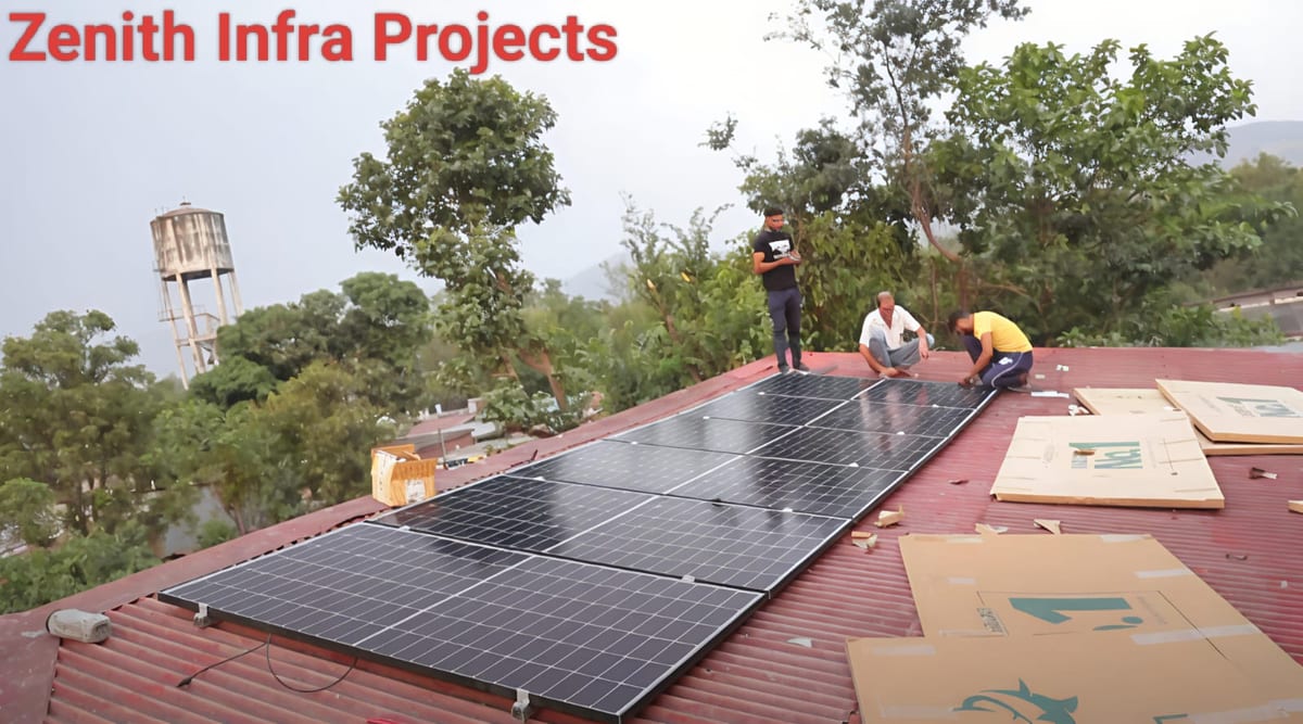 Workers installing solar panels on a red corrugated roof near a water tower