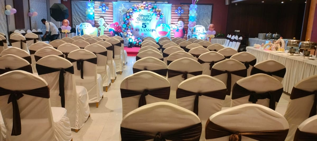 Banquet hall with rows of white-covered chairs, a decorated stage and buffet tables