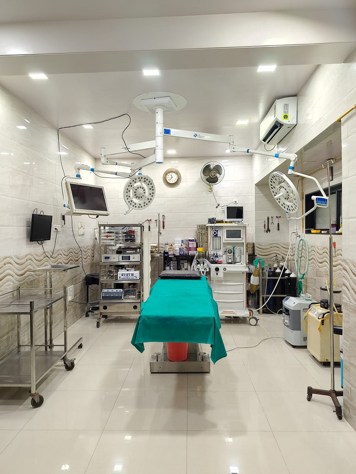 Bright operating room with a covered examination table, surgical lights and medical equipment