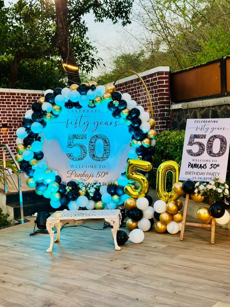 Birthday party display with balloon garland, gold number 50 and welcome signs