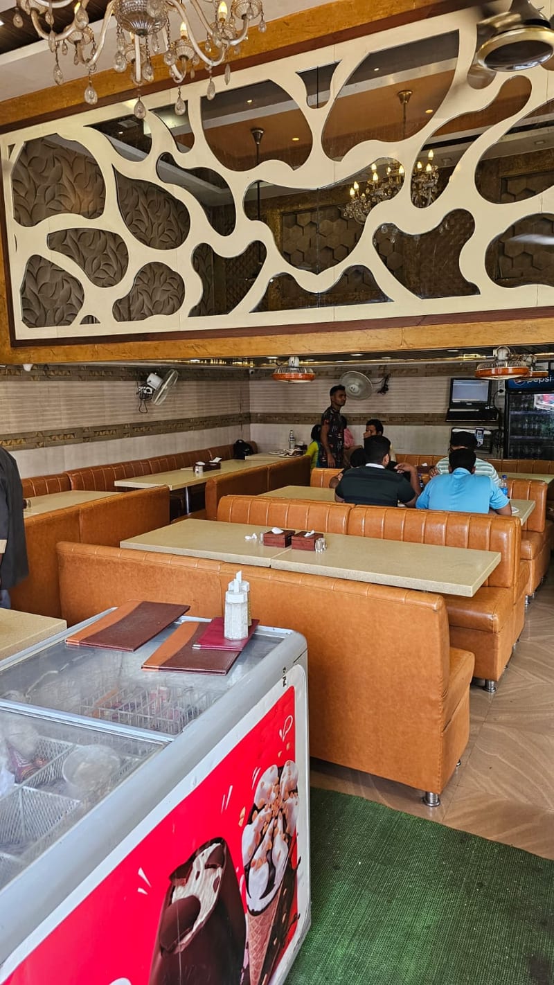 Farhang dining area with orange booths, decorative wall panel, chandelier and refrigerated display case