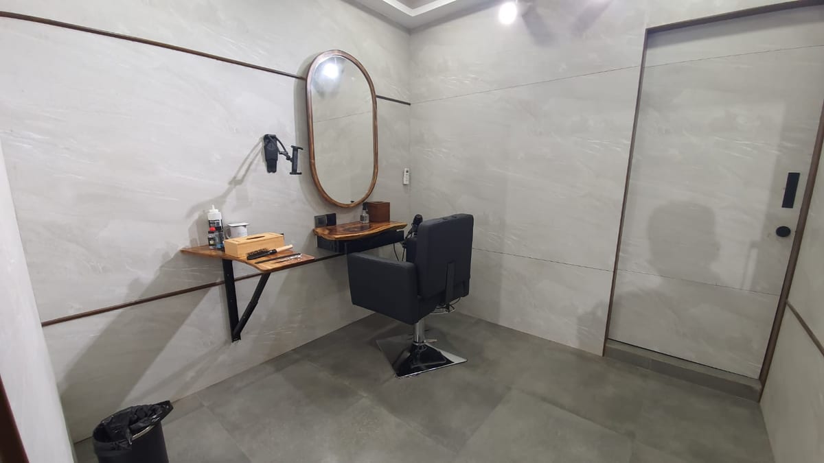 Styling station with an arched mirror, salon chair, shelf and glass door