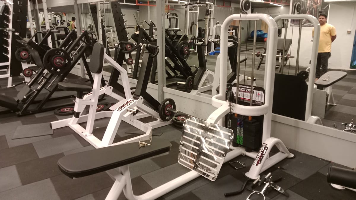 Mirrored gym interior with weight machines and benches at Unique Fitness Gym