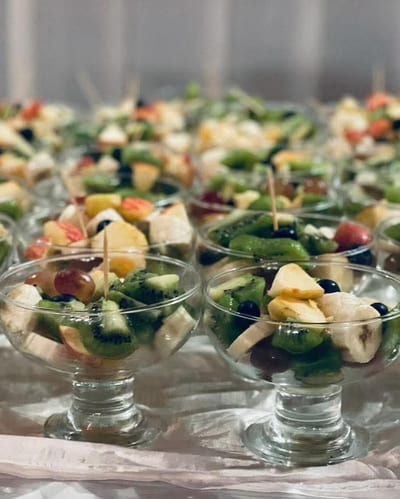Glass cups of mixed fruit salad arranged on a covered table