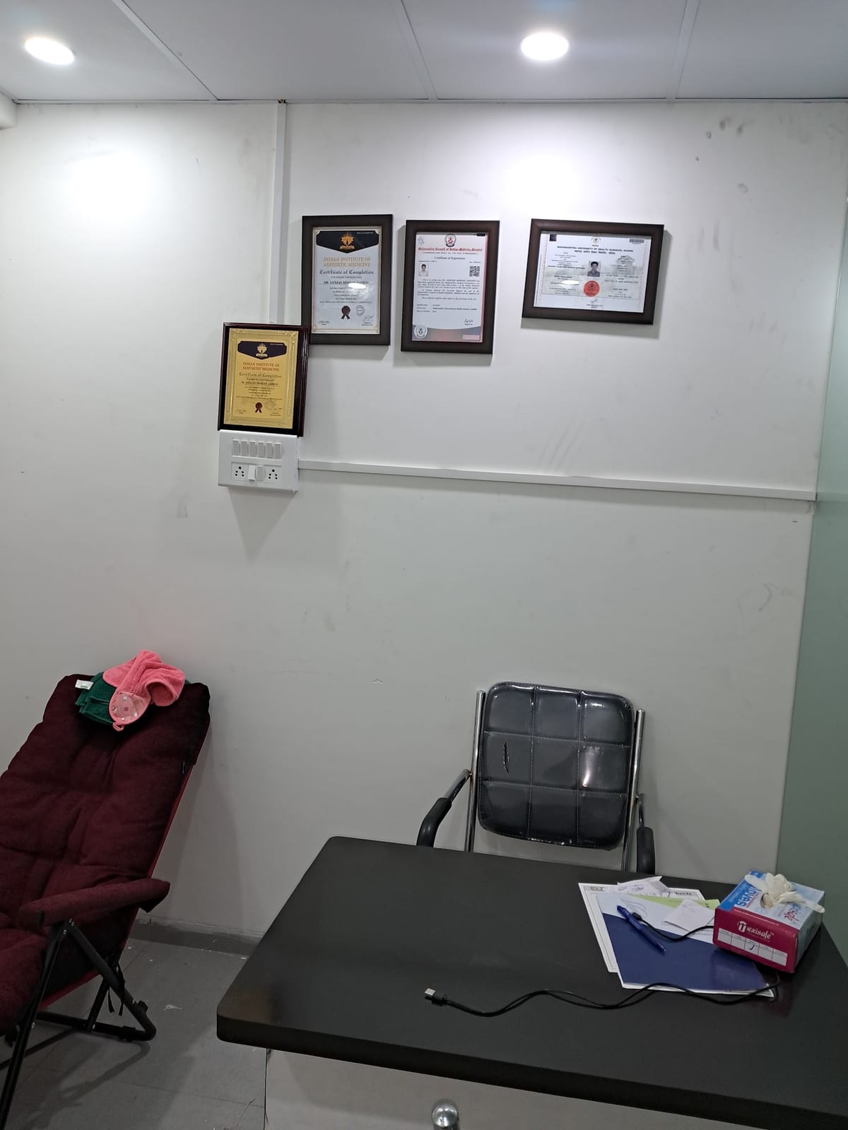 Waiting area with framed certificates, seating and a table with papers
