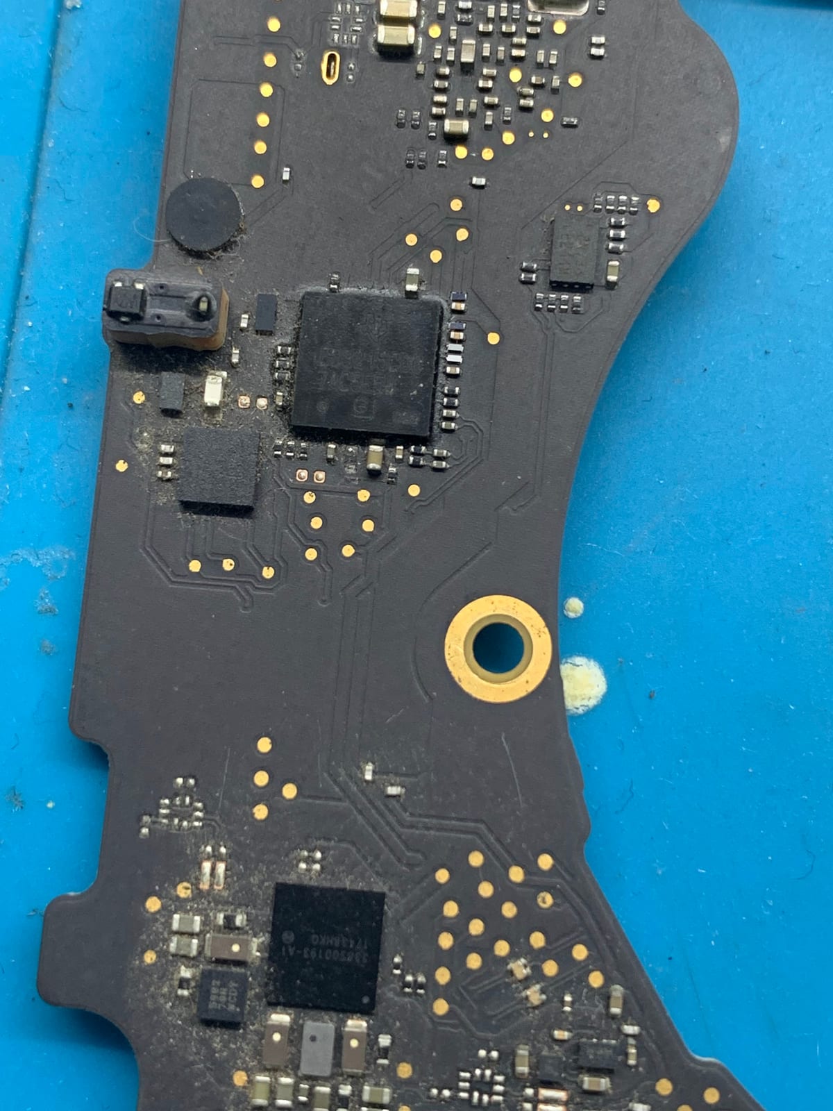 Black circuit board with chips and gold contacts on a blue work surface