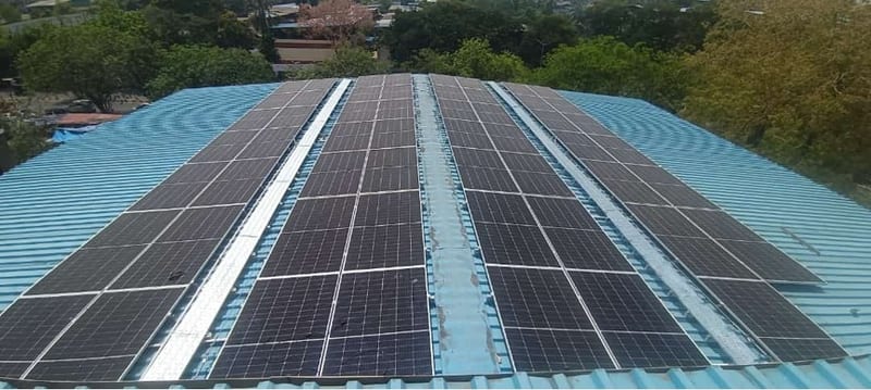Solar panels installed across a blue corrugated metal rooftop