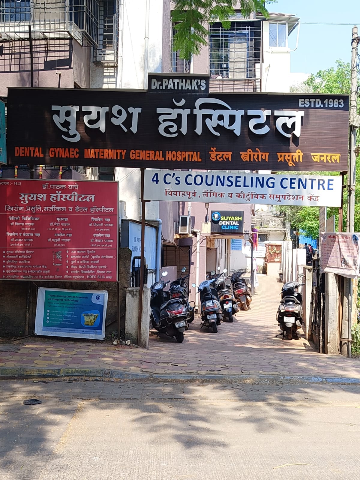 Hospital entrance with large bilingual Suyash Hospital signage and parked scooters