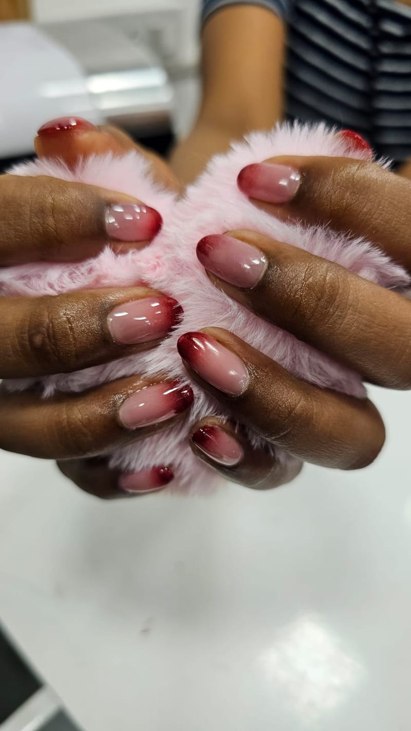 Hands with glossy pink manicured nails holding a pink fluffy item