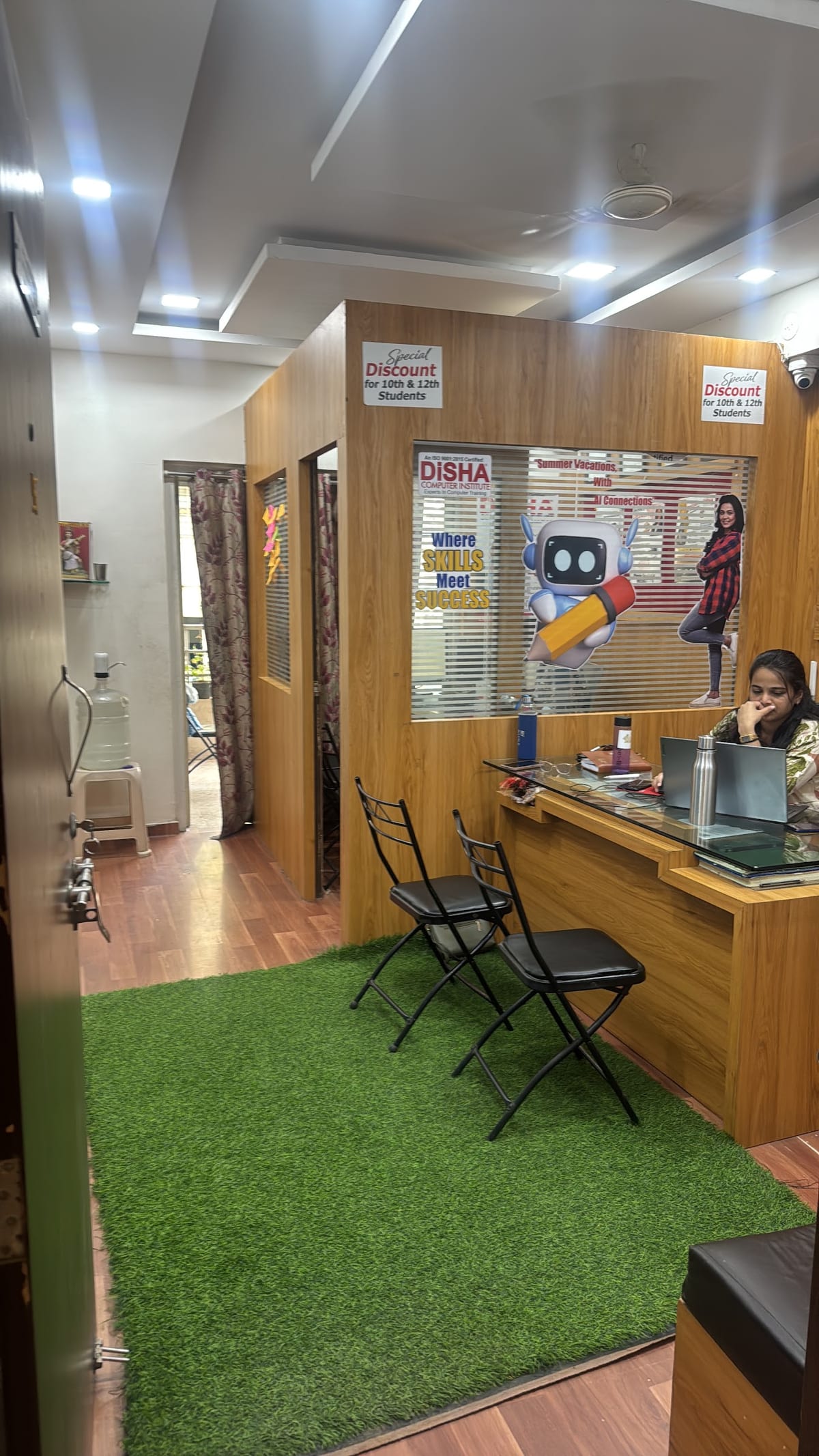 Reception area with wooden counter, seating, wall posters and a person at a desk