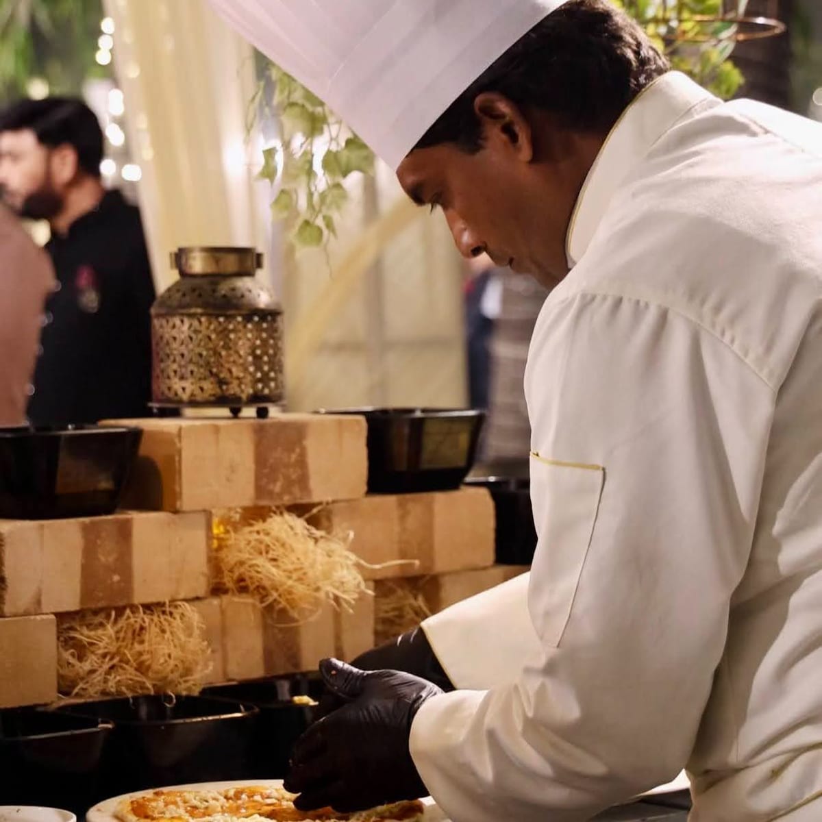 Chef in white uniform and hat preparing food at a buffet station