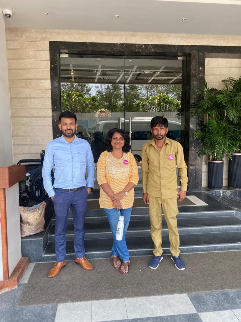 Three people posing at the glass entrance of the travel office