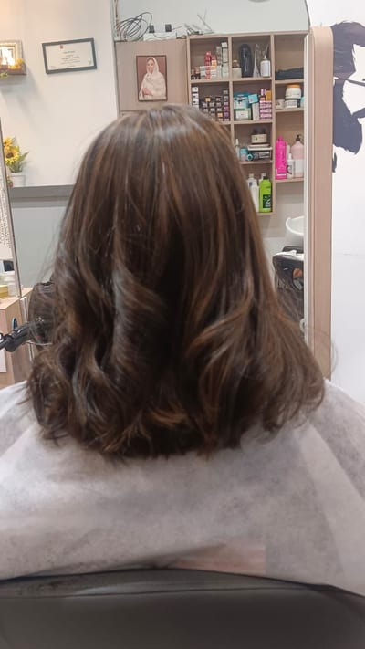 Client seated in a Unine Salon chair with freshly styled wavy brown hair, viewed from behind