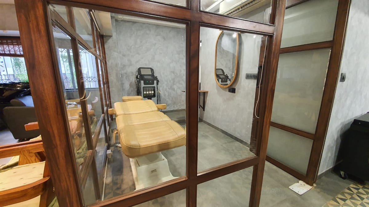 Treatment room with a padded table and equipment behind wood-framed glass partitions