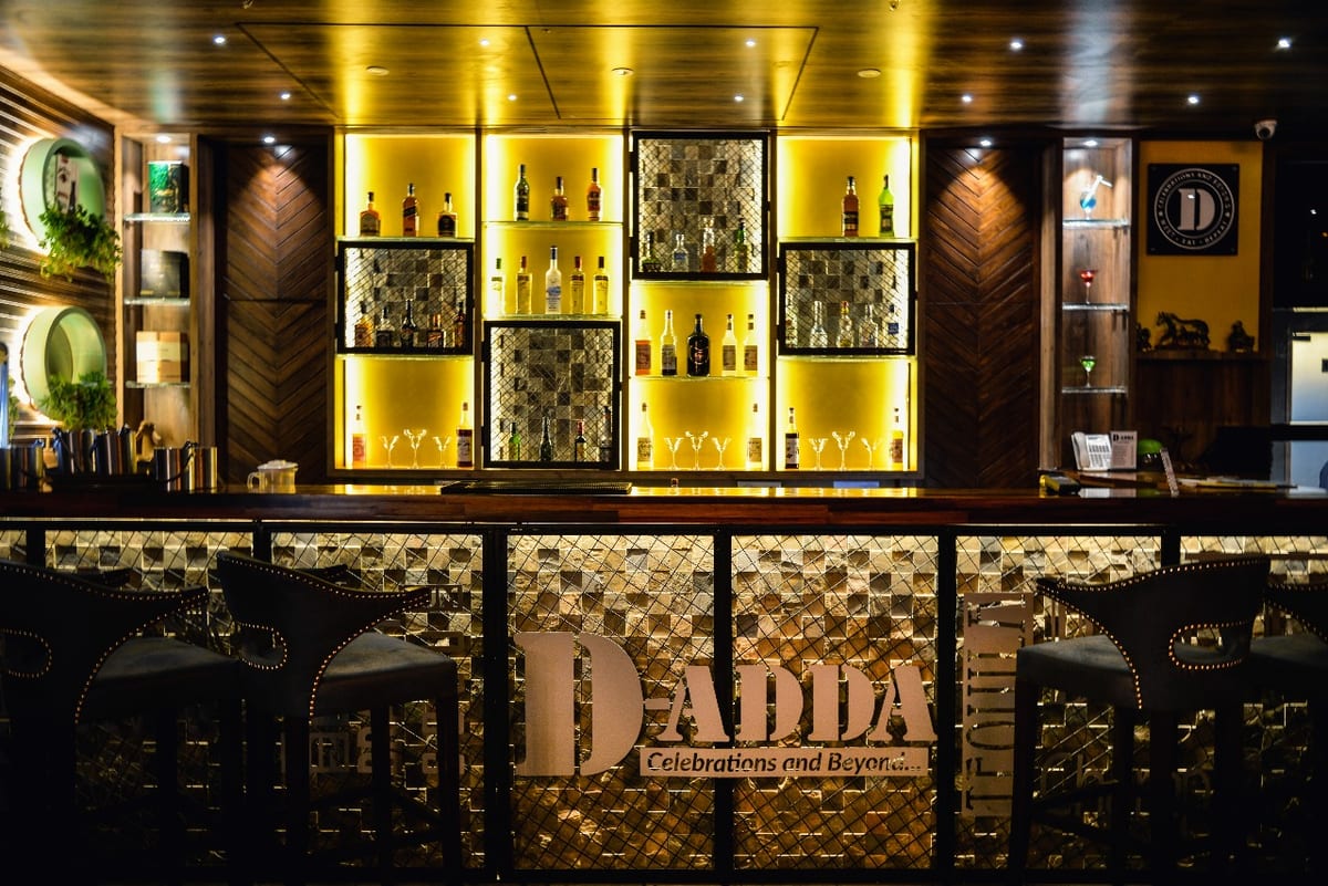 Bar counter marked DADDA with illuminated bottle displays and patterned panels
