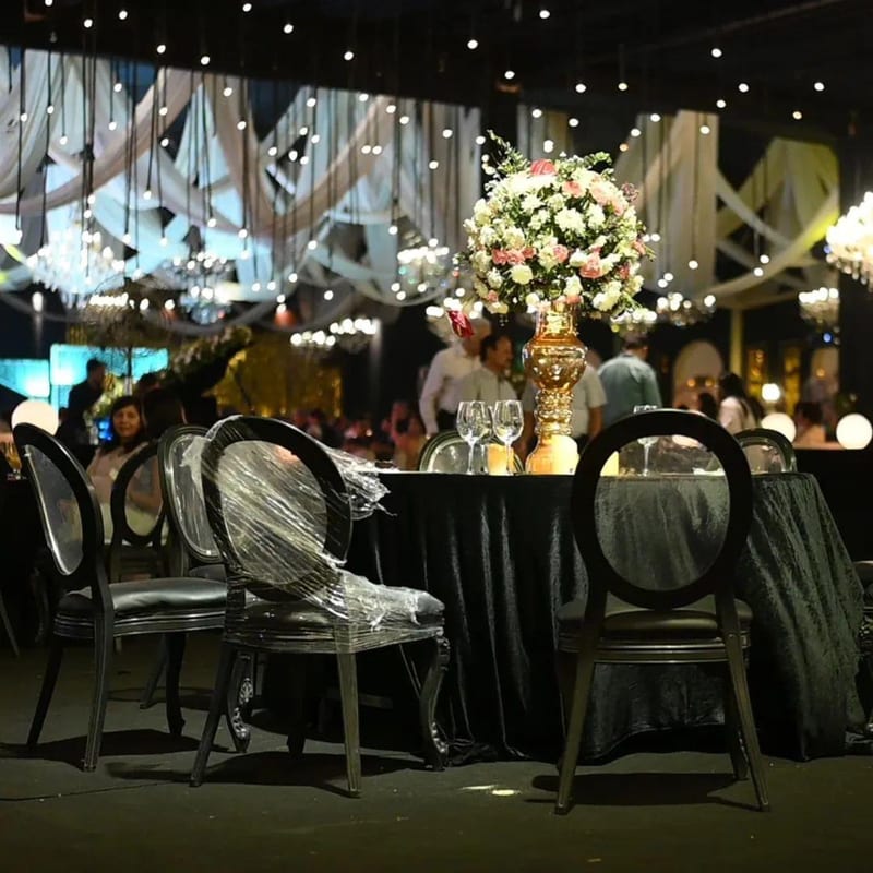 Round banquet table with floral centerpiece and covered chairs in an event hall