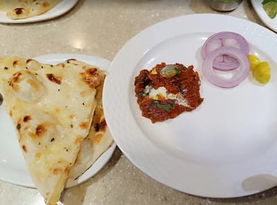 Flatbread served with red sauced curry, sliced onion and pickles
