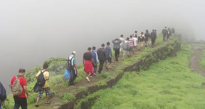 Travelers hiking along a misty grassy ridge