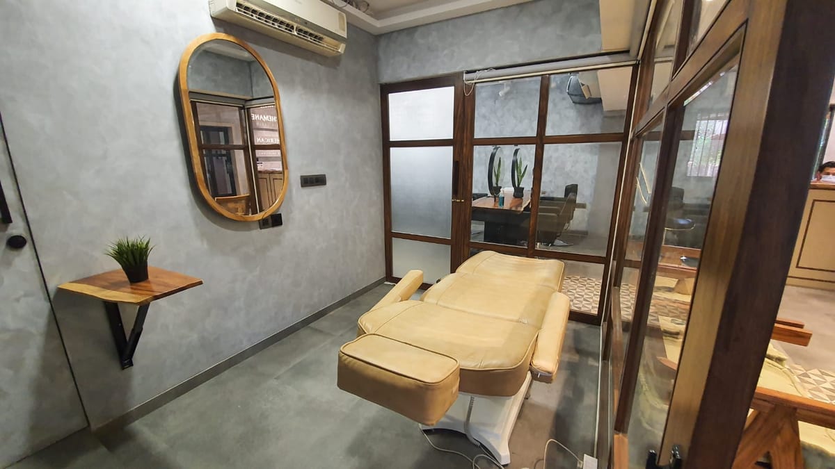 Room with a reclining cream chair, mirror, glass partitions and wall air conditioner