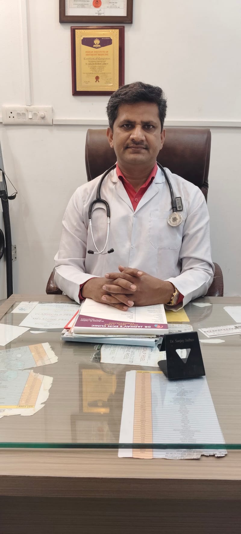 Doctor in a white coat with a stethoscope seated behind a desk