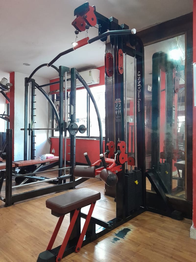 Strength-training equipment and a bench on a wooden floor with mirrored walls