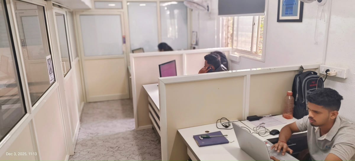 Office interior with partitioned workstations and two staff at computers