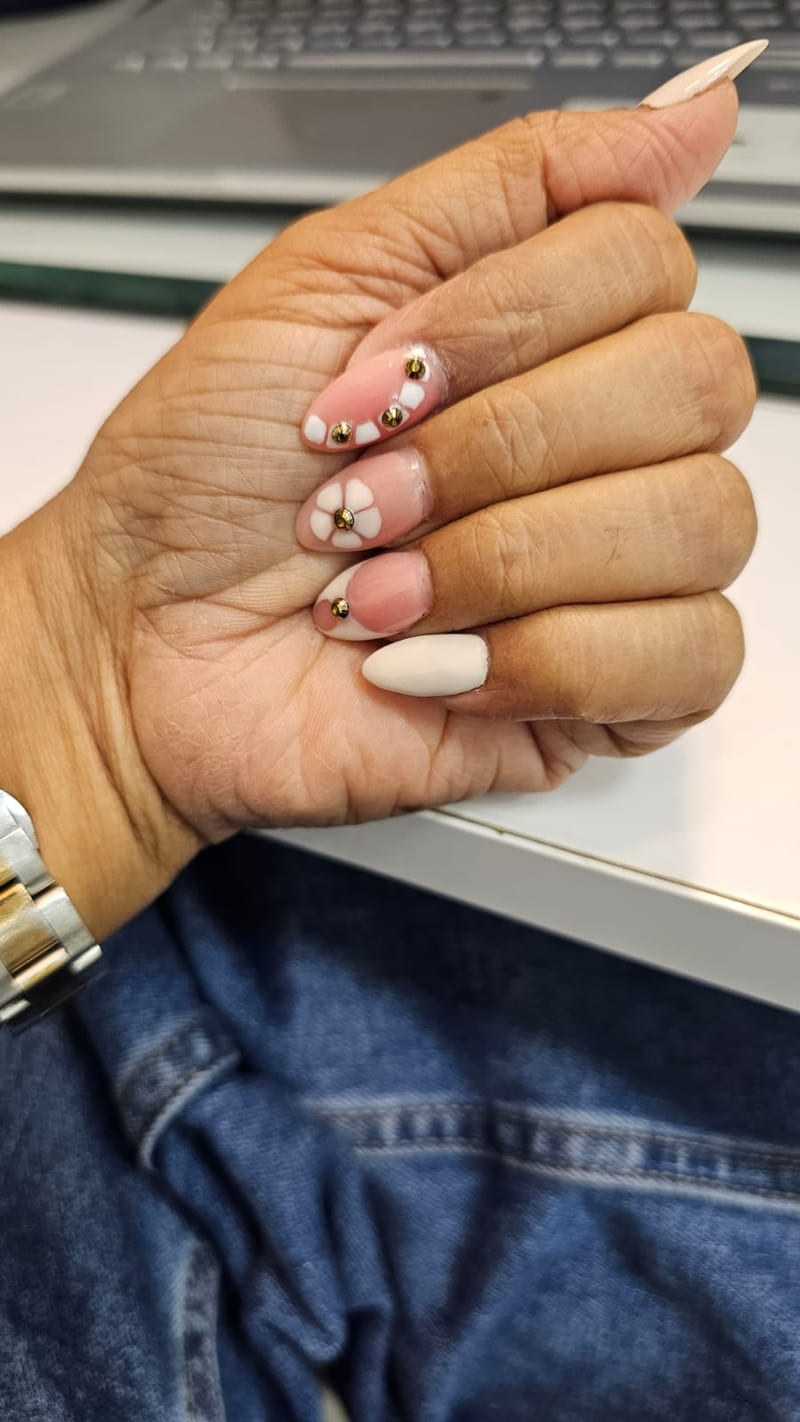Hand with pink and white decorated nails and rhinestone accents
