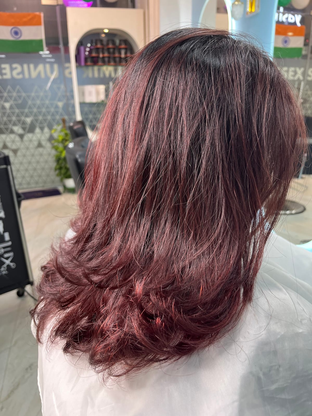 Client with long burgundy layered hair seated in the salon