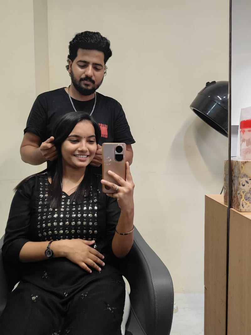 Stylist arranging a seated woman's hair in front of a salon mirror at Unine Salon