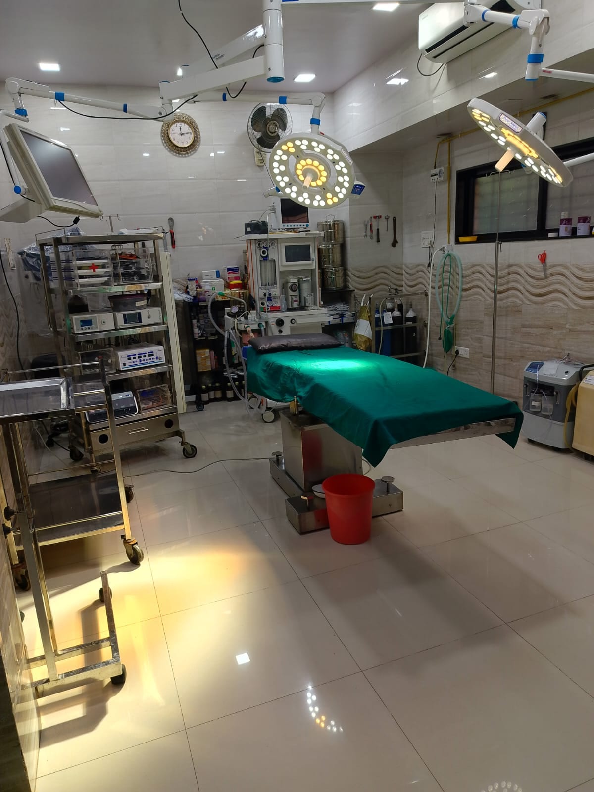 Operating room with covered surgical table, overhead lights and equipment carts
