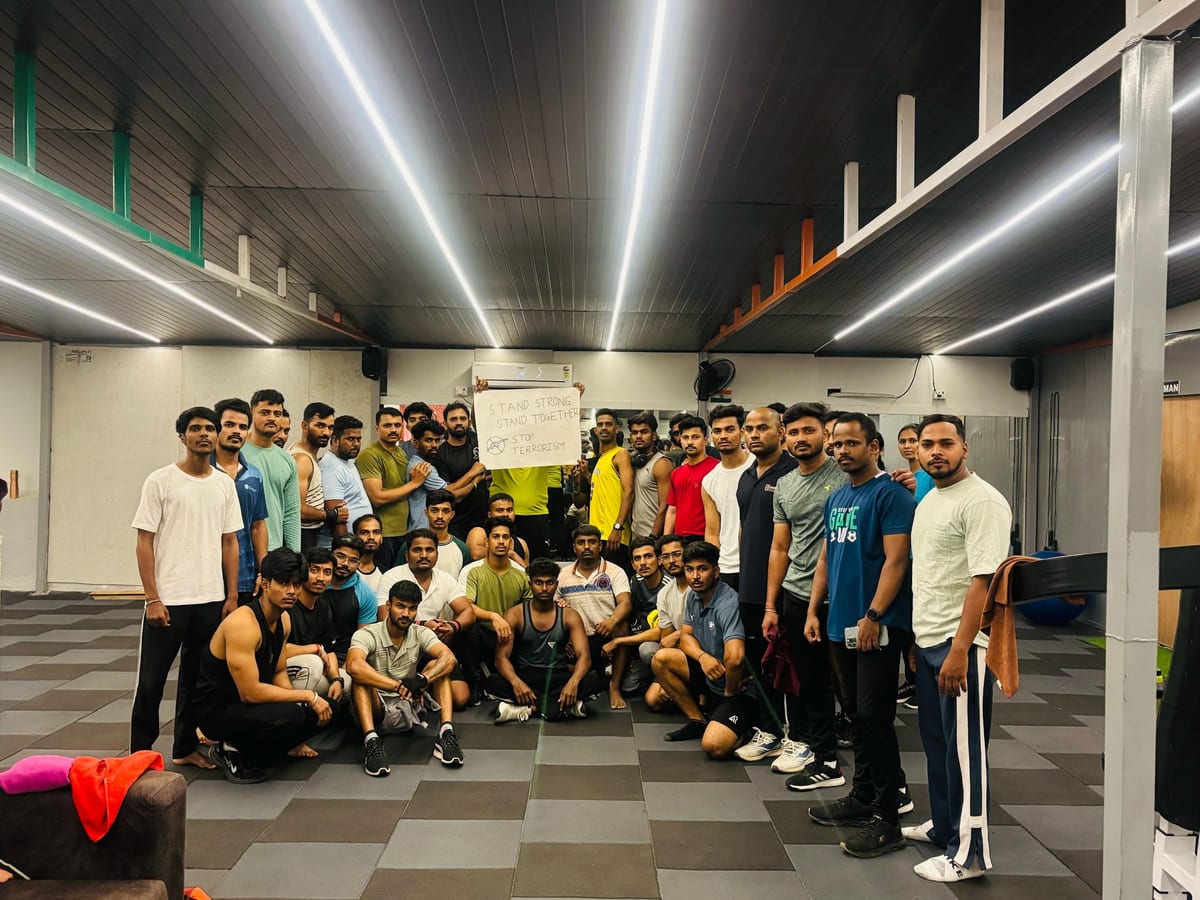 Large group of people posing together on the tiled floor in a spacious gym room