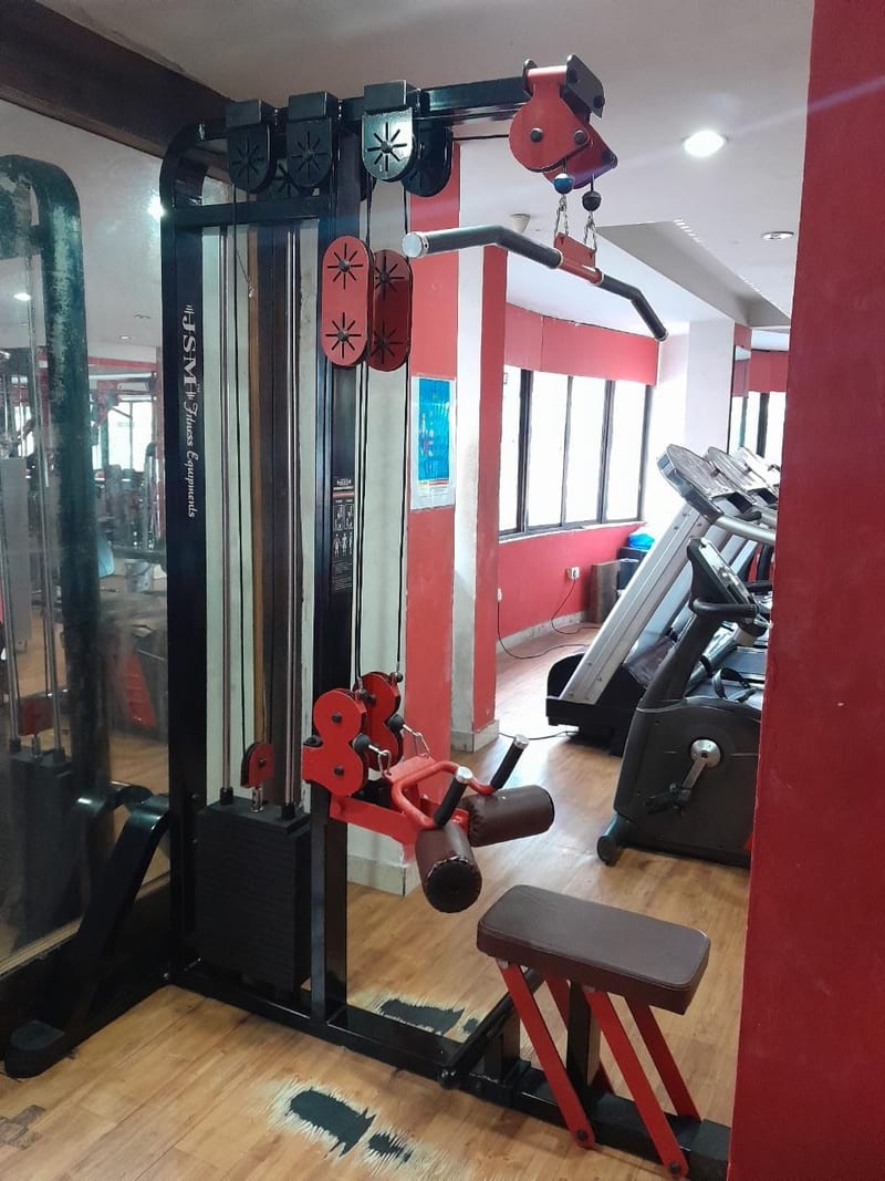Multi-station cable machine and cardio equipment with red wall accents